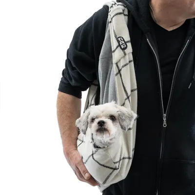 Torba na ramię w kratkę, niesiona przez osobę, mały pies bezpiecznie siedzi w torbie. Odpowiednia do transportu zwierząt domowych.