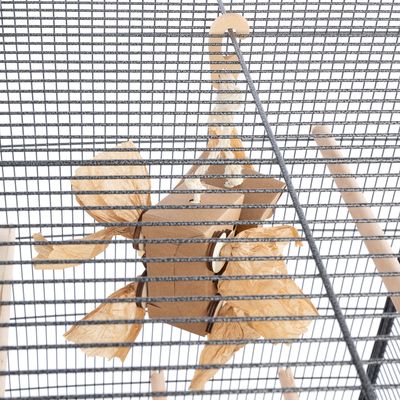 Jouet suspendu en carton et corde naturelle, accroché à la grille d'une cage pour oiseaux. Quatre extrémités en papier froissé visibles, perchoirs en bois en arrière-plan.