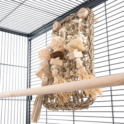 Geflochtenes Spielzeug aus Naturmaterialien mit Holz- und Bastelementen, befestigt an einem Käfiggitter. Geflochtenes Spielzeug aus Naturmaterialien mit Holz- und Bastelementen, befestigt an einem Käfiggitter.