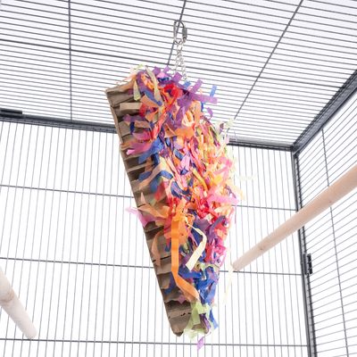 Zawieszana zabawka z tektury z kolorowymi paskami papieru, przymocowana do metalowego łańcucha w klatce.