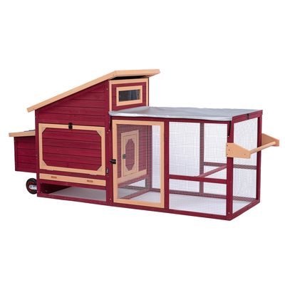 Poulailler en bois rouge et beige avec toit incliné, porte grillagée, zone extérieure couverte de grillage métallique et poignée latérale. Roues visibles à l’arrière.