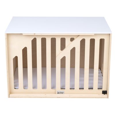 Niche ou caisse en bois clair avec barreaux verticaux, plateau blanc sur le dessus et coussin intérieur, marque Modern Living visible en bas au centre.