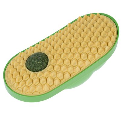 Зеленая игрушка с желтой ячеистой структурой и круглым травяным шариком в центре.