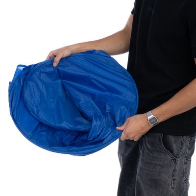 Person holder en sammenklappelig blå tunnel af plast, egnet til kæledyrsaktiviteter eller opbevaring af legetøj.