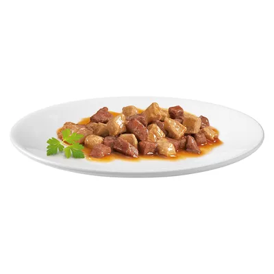 Närbild av köttbitar i sås på en vit tallrik, garnerad med färsk persilja.