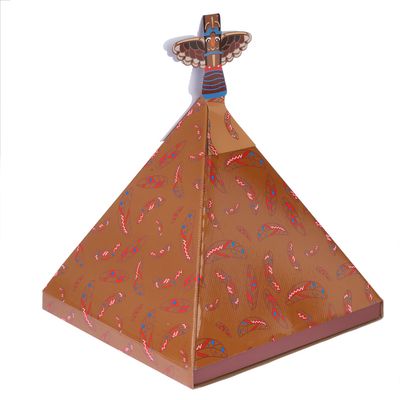 Objet pyramidal en carton décoré de plumes rouges et bleues, orné d’un totem stylisé au sommet. Aucun texte ou marque visible.