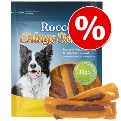 Pachet Rocco Chings Double cu imagine de câine, text vizibil: '100% reines naturprodukt', simbol promoțional procent roșu. Bucăți de snack pentru câini vizibile în fața ambalajului.