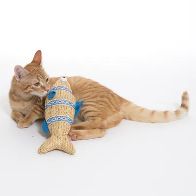 Червен котарак играе с плюшена рибка с синьо-червен десен и сини перки.