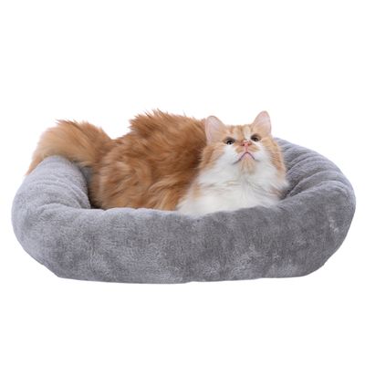 Röd och vit katt ligger i en grå, fluffig husdjursbädd.