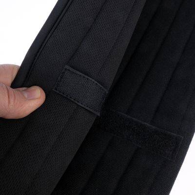 Primo piano di una chiusura in velcro nera su un tessuto, tenuta da una mano.