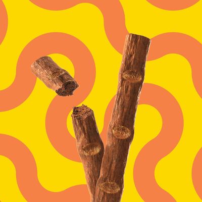 Bruna tuggpinnar med naturlig trästruktur, delvis brutna. Produkt för husdjur synlig mot gul bakgrund med orange vågmönster.