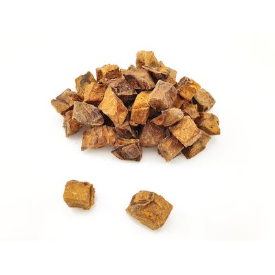 Torkade bruna köttbitar, löst staplade på vit bakgrund.