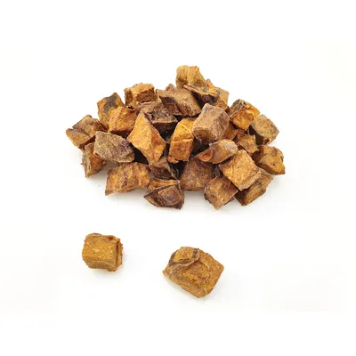 Morceaux cubiques de friandises brunes, posés en tas sur fond blanc, sans emballage ni marque visible.