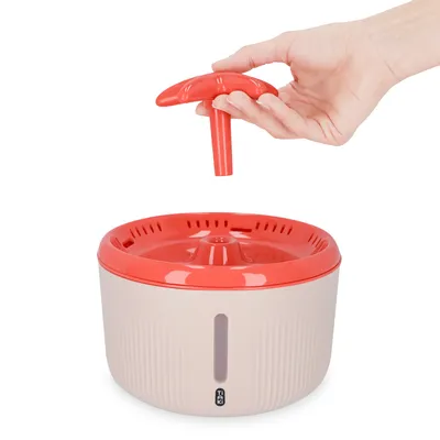 Hand showing removal of the red lid from a drinking fountain. White container with water level indicator and red rim visible.