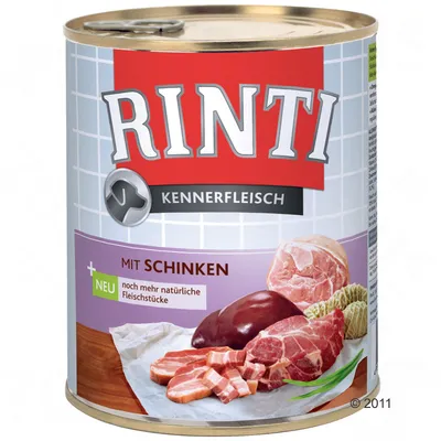 Lata de comida para perros Rinti Kennerfleisch. Texto visible: 'MIT SCHINKEN', 'NEU noch mehr natürliche Fleischstücke'. Imagen de varios tipos de carne en la etiqueta.
