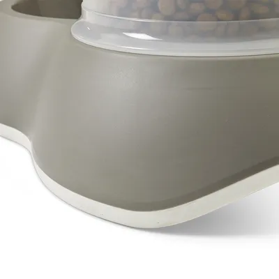 Distributore di cibo grigio con contenitore trasparente, riempito con crocchette. Adatto all’alimentazione automatica degli pet.