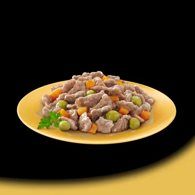 Assiette jaune contenant des morceaux de viande en sauce avec petits pois verts et dés de carottes, garnie d'une feuille de persil. Aucun emballage ou marque visible.