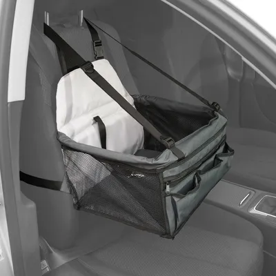 Siège auto pour animal avec sangles de fixation, parois en maille noire, coussin blanc amovible et poches zippées à l’avant, installé sur le siège passager d’une voiture.