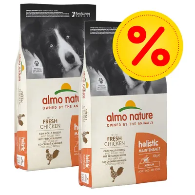 2 sacchi di Almo Nature Holistic Maintenance Medium Adult Dog con pollo fresco, 12 kg ciascuno, offerta evidenziata da simbolo percentuale giallo-rosso. Testo visibile in inglese e italiano.