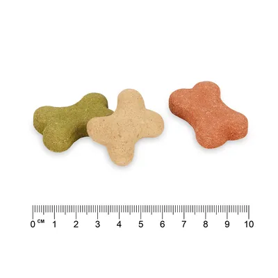 Három csont alakú kutyasnack zöld, bézs és piros színben. Az alsó skála kb. 5 cm hosszúságot mutat.