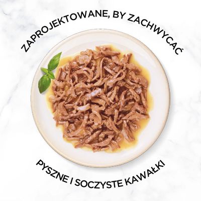 Talerz z kawałkami mokrej karmy w sosie, obok liść bazylii. Widoczny tekst: 'Zaprojektowane, by zachwycać. Pyszne i soczyste kawałki'.