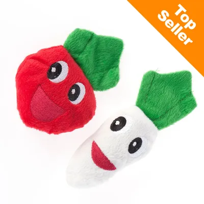 Två mjuka leksaker i form av grönsaker med broderade ansikten, en röd och en vit, båda med gröna blad. Text: Top Seller i orange hörn.