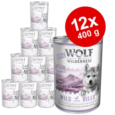 12x400 g Wolf of Wilderness Little Wild Hills dåser. Synlig tekst: 100% grain-free, Wild Hills Junior, 400 g. Billede af bjerglandskab og ulveunge på emballagen.
