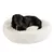 Chien noir allongé sur un coussin rond en tissu blanc, surface douce et moelleuse visible.