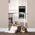 White safety barrier for doors, installed in a kitchen. Dog lying in front, indicating the barrier as a safety measure.