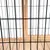 Vue rapprochée d’une structure en métal noir avec fond et cadre en bois clair, montrant les matériaux utilisés pour une cage ou un enclos.
