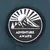Badge with mountain, sun and trees illustration, featuring the text 'ADVENTURE AWAITS'.