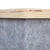 Nahaufnahme einer Holzplatte mit grauem Filzbezug, zeigt Materialkombination für Möbel oder Zubehör.