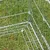 Detailopname van een metalen ren met traliewanden en stevige verbindingsclips op een grasveld.