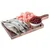 Trois poissons entiers, morceaux de viande crue rose et bol de petites baies rouges sur une planche en bois, ingrédients visibles pour alimentation animale.
