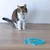 Katze sitzt vor einer blauen Fisch-förmigen Schleckmatte mit Futter darauf, zeigt Anwendung des Produkts.