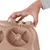 A hand shows how a removable part of a beige feeding bowl system is attached or removed.