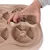 Hand lyfter del av beige aktivitetsleksak i plast med flera runda fack och snurrande delar, avsedd för husdjur.