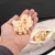 Hand hält Schaumstoff-Füllmaterial, daneben ein geöffnetes Fach mit ähnlichem Material. Geeignet für Nachfüllung von Kissen oder Polstern.