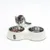 Tiaki double bowl made of stainless steel with white holder, filled with cat food. Small cat looking at the bowl.