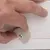 Main ajustant une molette en plastique beige fixée par une vis sur une surface en bois clair. Aucun texte ou marque visible.