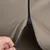 Close-up van een bruin stoffen materiaal met een zwarte ritssluiting die wordt geopend.
