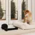 Dog sitting in a cream-coloured dog bed next to a black rope chew toy.