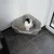 Corner cat litter tray made of grey plastic with cat, filled with cat litter. Suitable for space-saving placement in corners.