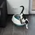 Toilette per gatti con bordo semi-alto, bianco-blu, riempita di lettiera. Gatto che esce dalla toilette. Adatta per interni con pavimento piastrellato.