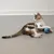 Gatito joven juega con una pelota de juguete azul y verde sobre suelo gris.