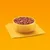 Bowl filled with dry pet food pieces and small chunks, placed on a folded yellow cloth against an orange background.