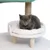 Graue Katze sitzt auf einem weissen, gepolsterten Katzenbett mit Holzbeinen. Teil eines Kratzbaums sichtbar im Hintergrund.