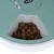 Food dispenser with green lid and compartment filled with brown dry food cubes.