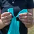 Person showing how a green dog waste bag is pulled apart at the ends.