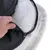 Vue rapprochée d’une main ouvrant la housse zippée d’un coussin pour animaux, montrant l’intérieur en tissu matelassé blanc et la base antidérapante noire à pois.